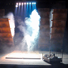 "Angels In America" at Carnegie Mellon. Beams of bright light shine down on Prior Walter while laying in bed as the wall falls around him.