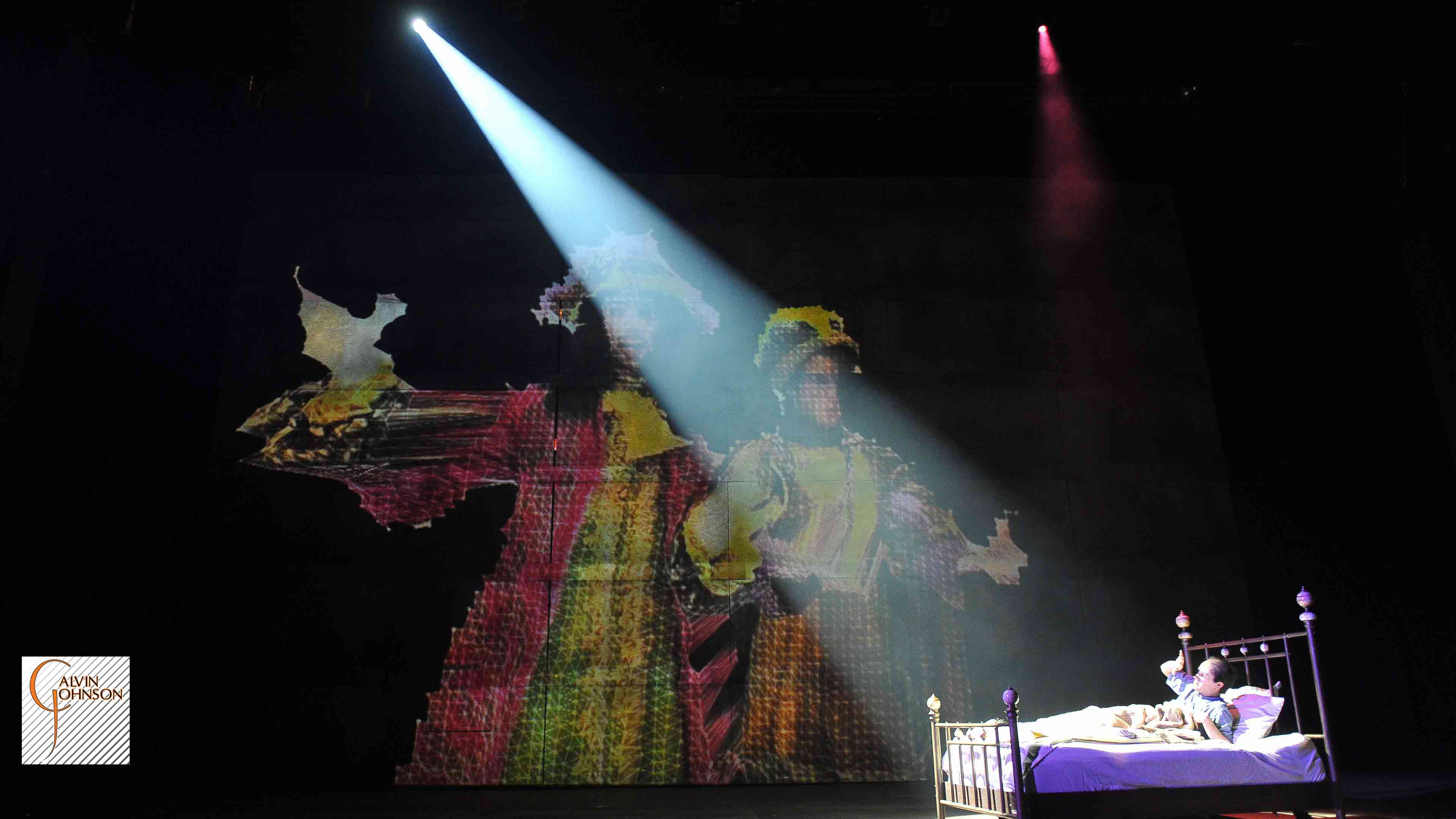 A performance of "Angels In America" at Carnegie Mellon. Bright beam of light on Prior Walter in bed as he is visted my digital images of ghost.