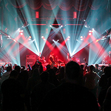 Hip Hop artist B.o.B performing in front of purple and green beams of light at a concert with DJ Shawty Slim.