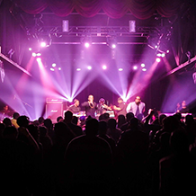 Hip Hop artist B.o.B performing in front of purple and green beams of light at a concert with DJ Shawty Slim.