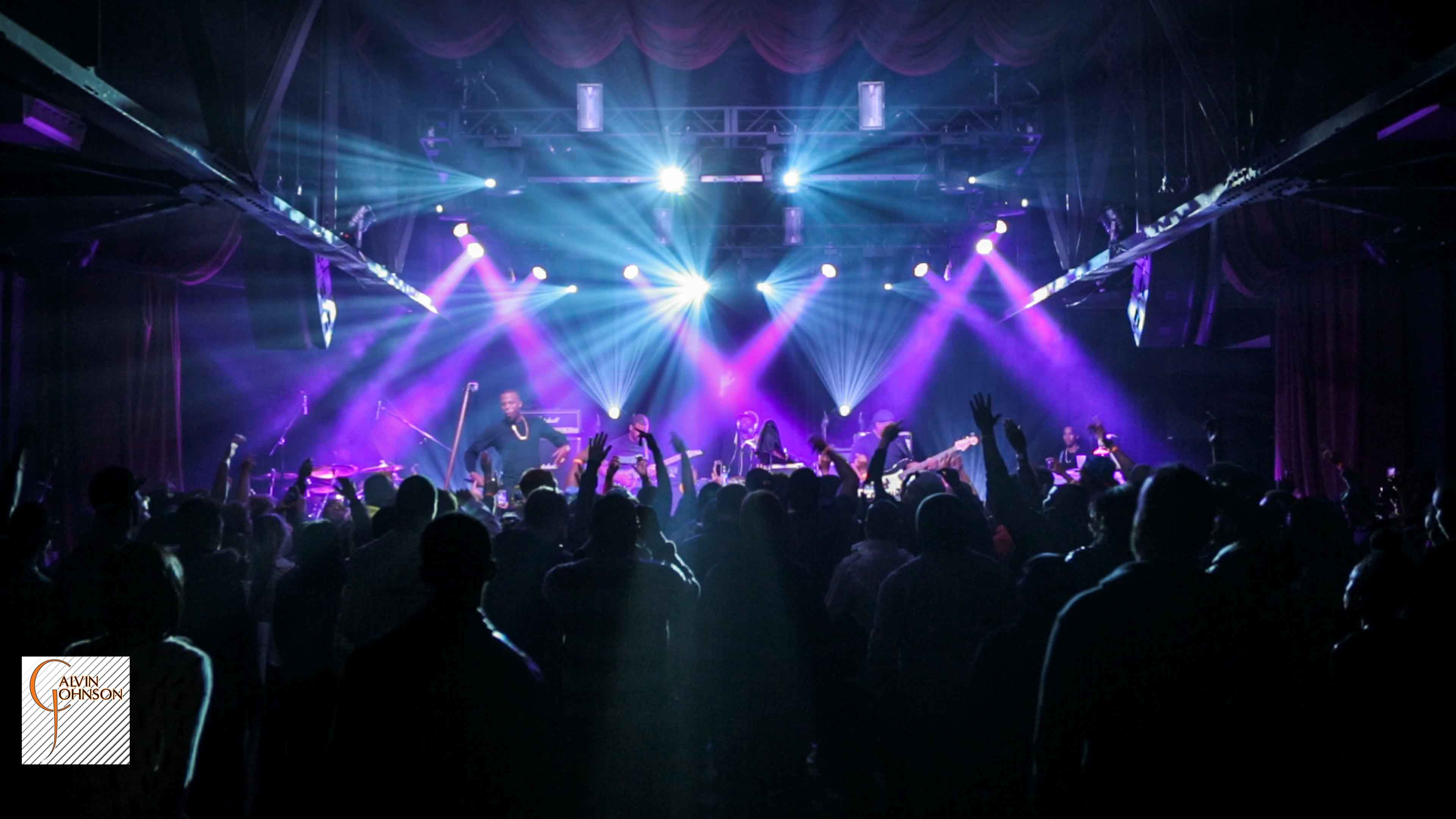 Hip Hop artist B.o.B performing in front of purple and green beams of light at a concert with DJ Shawty Slim.