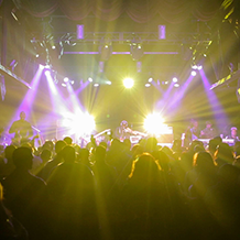 Hip Hop artist B.o.B performing in front of purple and green beams of light at a concert with DJ Shawty Slim.