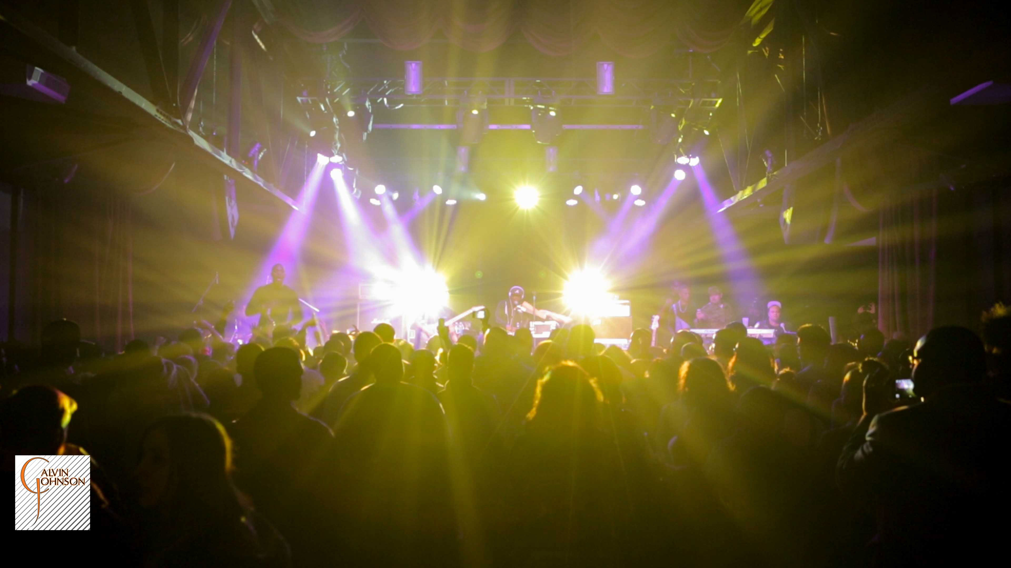 Hip Hop artist B.o.B performing in front of purple and green beams of light at a concert with DJ Shawty Slim.