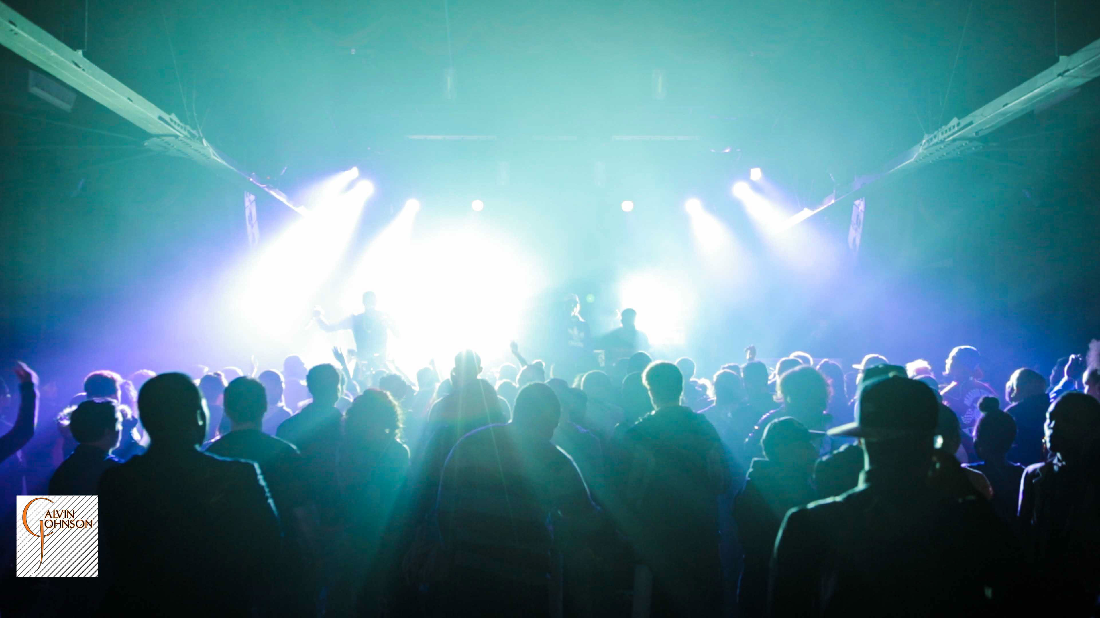 Hip Hop artist B.o.B performing in front of purple and green beams of light at a concert with DJ Shawty Slim.
